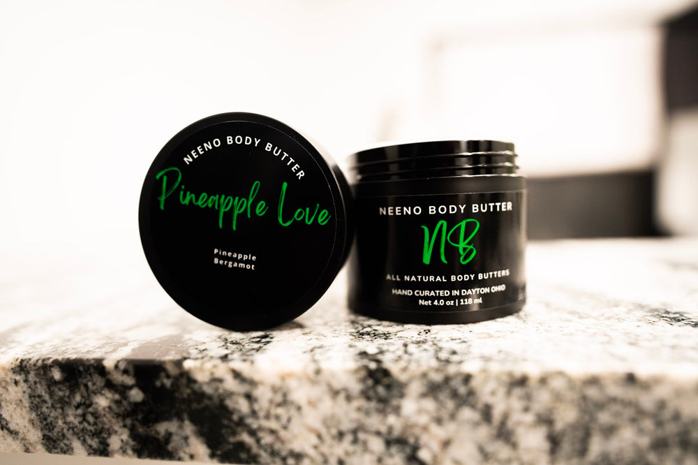Pineapple Love whipped body butter in a Neeno Body black jar on a marble countertop