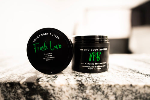 Fresh Love body butter by Neeno,  in an elegant black jar with a matching black lid. The product name is displayed in white cursive font on the lid, with the tagline "All Natural Body Butter" 