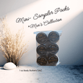 Six mini jars of Neeno Body Butter next to a white rock and tan decorative shrubs