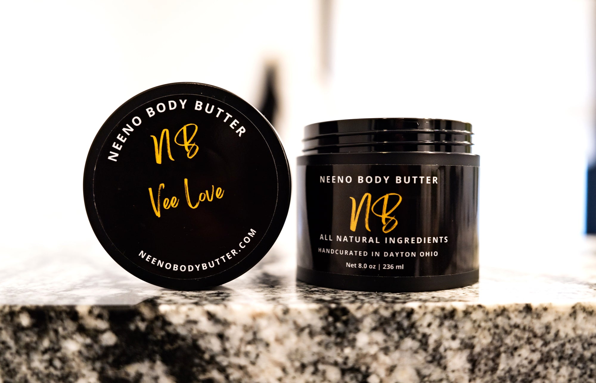 Vee Love whipped body butter in a Neeno Body black jar on a marble countertop