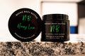Honey Love whipped body butter in a Neeno Body branded black jar on a marble countertop