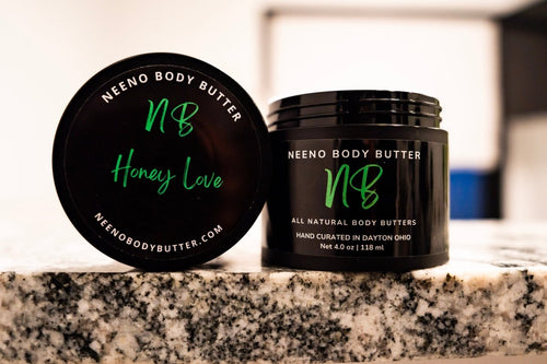 Honey Love whipped body butter in a Neeno Body branded black jar on a marble countertop