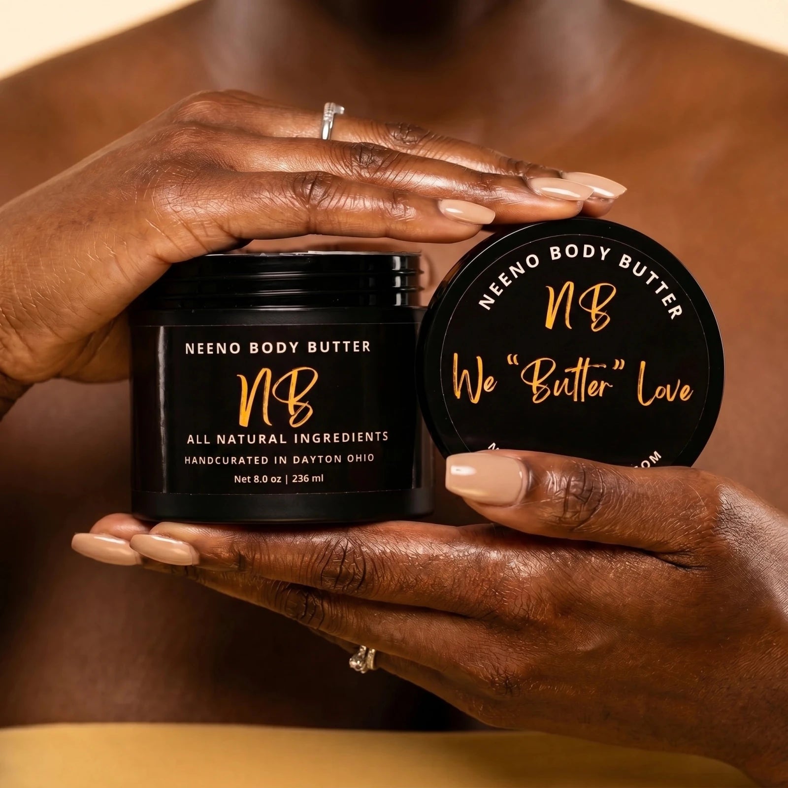 Two hands holding a Neeno Body Butter container with visible branding.